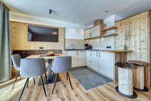 A modern kitchen with a dining area, wooden accents, and a flat-screen TV. - Modern Apartment with 2 Bedrooms & Panoramic Views – Apis (Avelengo)