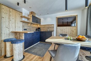 Eine moderne Küche mit Holzakzenten, ein Essbereich mit Tisch und Stühlen sowie ein Blick in den angrenzenden Wohnraum.