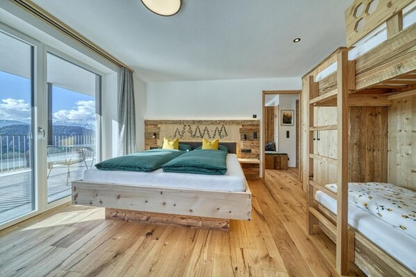 A bedroom with a wooden bed, a balcony with a view of mountains, and a wooden headboard. - Beautiful Apartment with Mountain View – Silva (Avelengo)