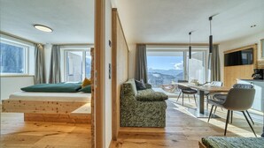 A modern living room with a sofa, a dining table, and a view of mountains. - Beautiful Apartment with Mountain View – Silva (Avelengo)
