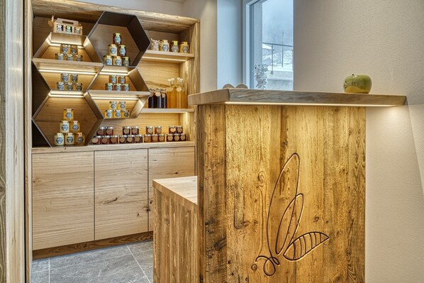 A wooden counter with honey jars and a honey dipper. - Beautiful Apartment with Mountain View – Silva (Avelengo)