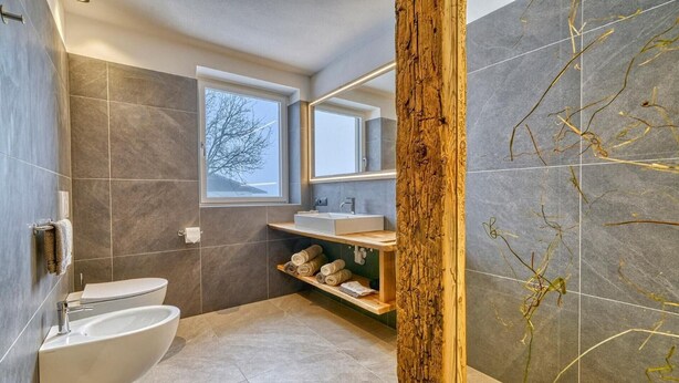 Une salle de bain moderne équipée de toilettes, d’un lavabo et d’étagères intégrées.
