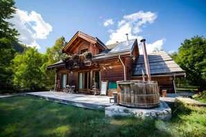 Una cabaña de madera con balcón, un muelle de madera y un barril metálico grande.