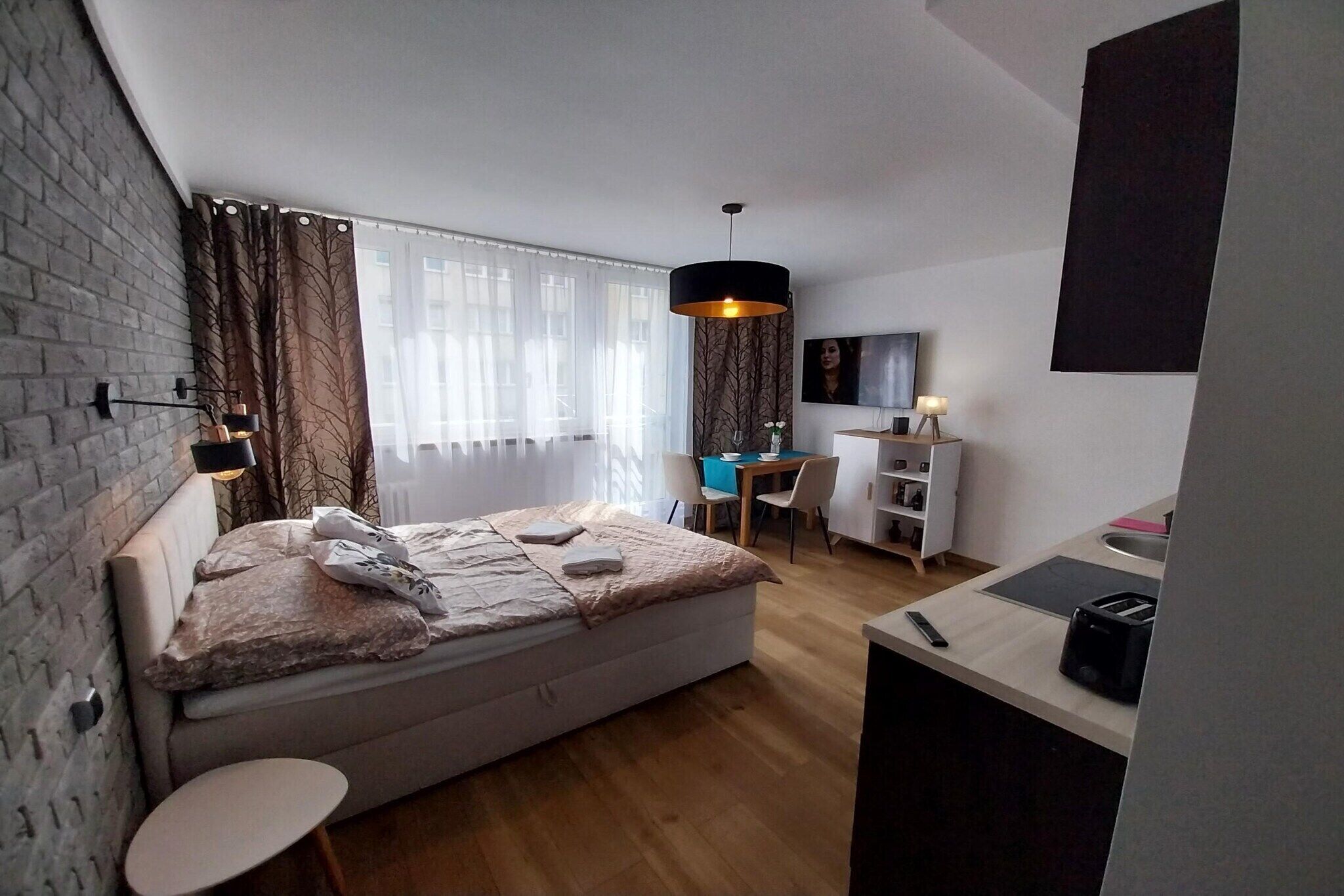 Un dormitorio con cama, mesita de noche y zona de escritorio con silla.