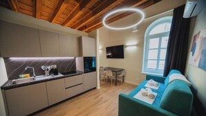 A modern kitchen with wooden beams, a dining area with a table and chairs, and a green sofa with towels.