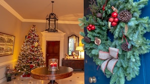 A Christmas tree, a lit candle, and a wreath on a door.