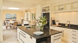 A modern kitchen with a central island, white cabinetry, and a dining area with a table and chairs.