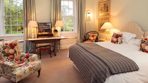 A hotel room with a bed, desk, chair, and two lamps.