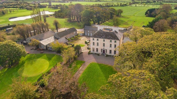 A large estate with a central building, surrounded by green fields and trees.
