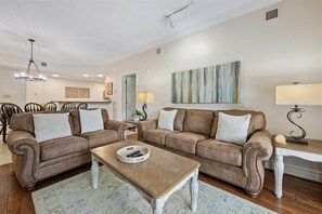 A living room with two brown leather sofas, a wooden coffee table, a white side table, and a painting on the wall. - 🌲Baskins Creek 206: Cozy Gatlinburg Condo | Balcony & Hot Tub Await🏔️ (Gatlinburg)