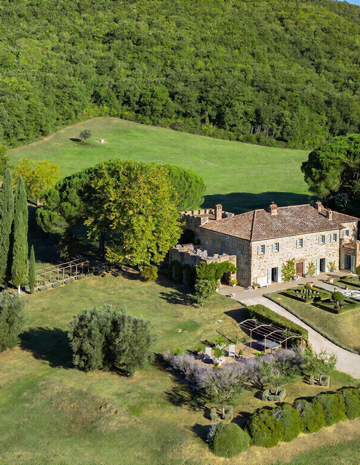 Un edificio de piedra con un jardín y un árbol grande al frente.