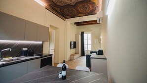 Une cuisine moderne avec un plan de travail en marbre, une bouteille de vin et un plafond orné de motifs complexes.