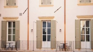Une façade d’immeuble avec de nombreuses fenêtres, un balcon avec des chaises et une balustrade.