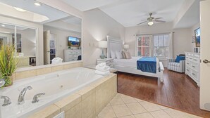 Un dormitorio espacioso con una cama grande, un vestidor y un baño con bañera.