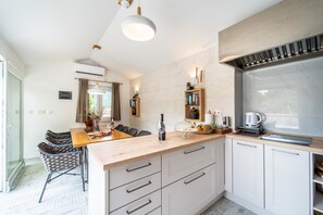 A modern kitchen with a wooden countertop, white cabinets, and a built-in stove. - Villa Aurora: A Luxurious Stone Retreat in Dalmatia (Slivno)