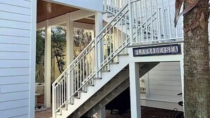 Una escalera conduce a un porche cubierto con un letrero que dice 'Fleur de Sea'.