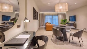 A modern hotel room with a dining area, a sofa, and a large window with curtains. - Cozy Rabat 1BR with Private Balcony (Rabat)