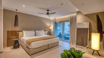 A modern hotel room with a bed, ceiling fan, large windows, and a view of the outside.