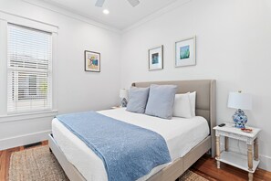 Ein Schlafzimmer mit einem Bett, einem Nachttisch, einer Lampe und einem Fenster mit Jalousien.