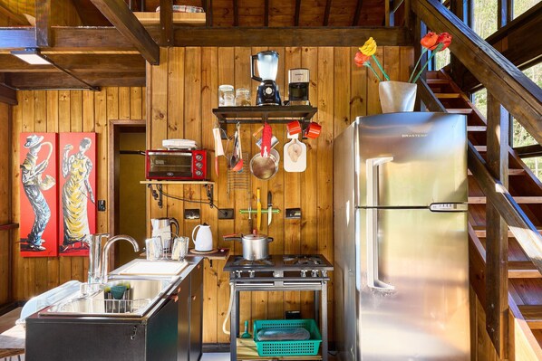 A compact kitchen with a refrigerator, stove, and various utensils.