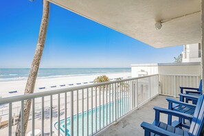 A balcony with a view of the beach, a pool, and blue chairs. - Stunning Sand Castle I 308 (Indian Shores)