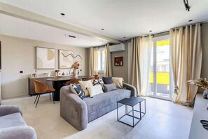 Un salon moderne comprenant un canapé, une table basse et un coin repas avec des chaises.