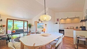 Una cocina moderna con armarios blancos, una mesa de comedor y un ventanal grande.