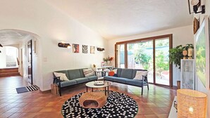 Una sala de estar con un sofá, una mesa de centro, un tapete estampado y un ventanal grande.