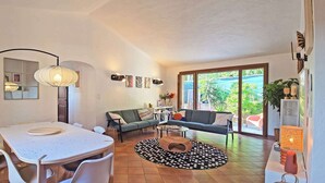 Una sala de estar moderna con una mesa de comedor, sofá y un ventanal grande.