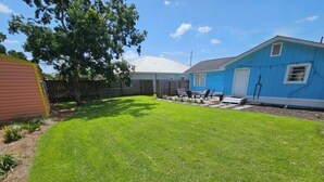 Ein Garten mit gepflegtem Rasen, Holzfence und einem blauen Haus.