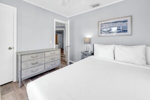 A bedroom with a large bed, a dresser, a nightstand, and a framed picture on the wall. - Walk to Beach-Backyard with Games-The Blue Marlin (Panama City Beach)