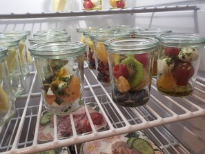A refrigerator shelf with multiple glass jars containing various fruits and vegetables. - Landgut Apfelrose (Friedrichshafen)
