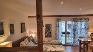 A room with a wooden bed, a desk, and a dining table. - Landgut Apfelrose (Friedrichshafen)