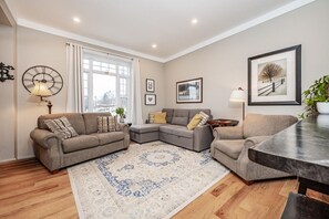 Un salon comprenant un canapé, une table basse, un tapis et une horloge murale.