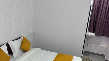 Habitación de hotel con una cama, un control remoto, una toalla, un lavamanos y una cortina de ducha.