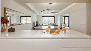 A modern kitchen with a large island, a dining area with a round table, and large windows offering a view. - Acqua Gem by Homie in Funchal (Funchal)