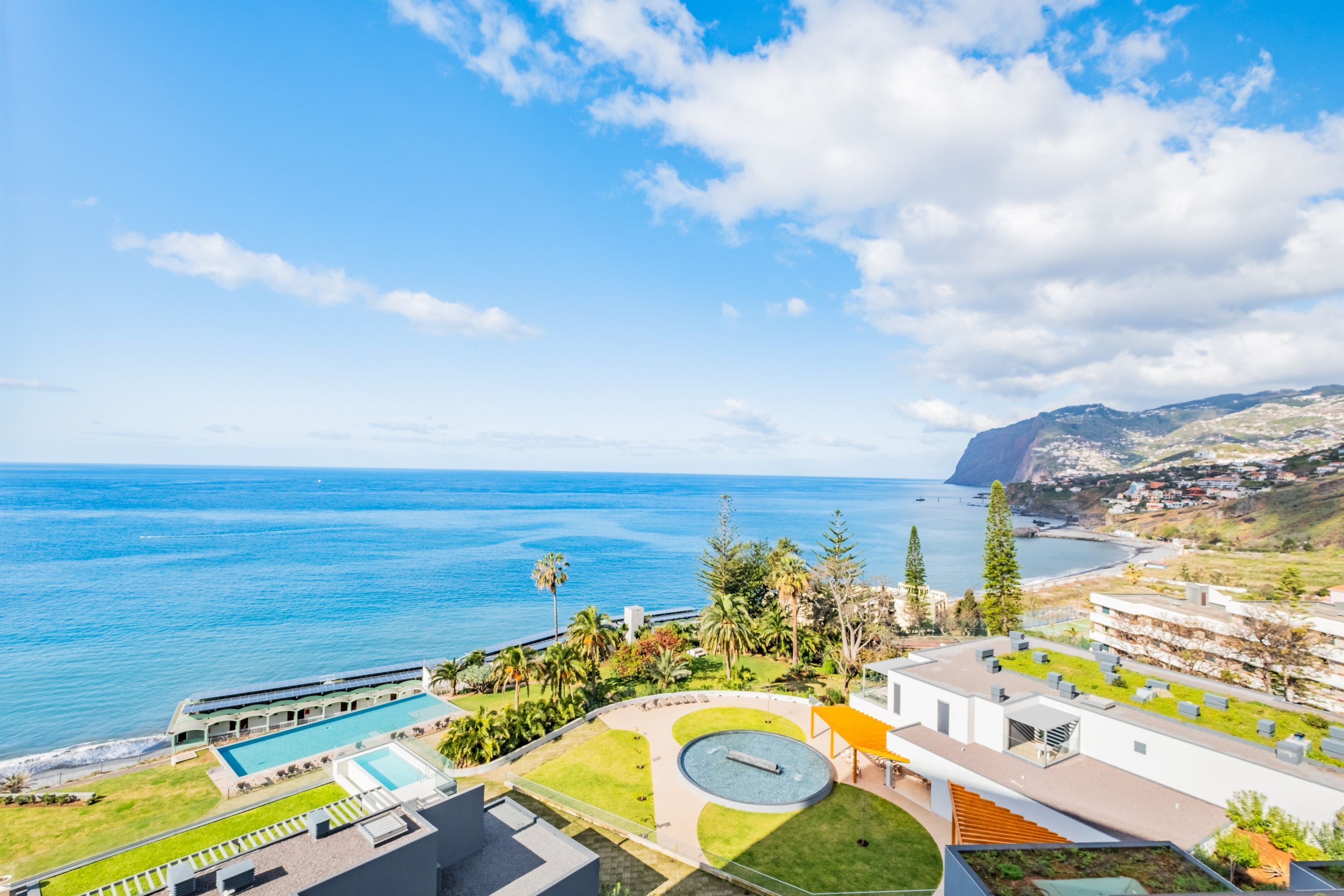 Un hôtel en bord de mer doté d’une piscine, d’un bassin circulaire et offrant une vue sur la mer et les montagnes.