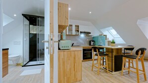 A modern kitchen with a wooden island, bar stools, and a skylight.