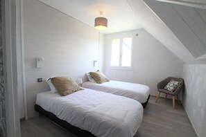 A bedroom with two beds, a window, a lamp, and a chair. - 200 meters from the beach with access to a heated pool – Family-friendly vacation rental (Port-Bail-sur-Mer)