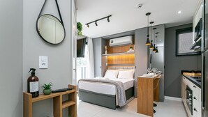 Een moderne slaapkamer met een bed, nachtkastje en een klein houten plankje met een plant en een fles.
