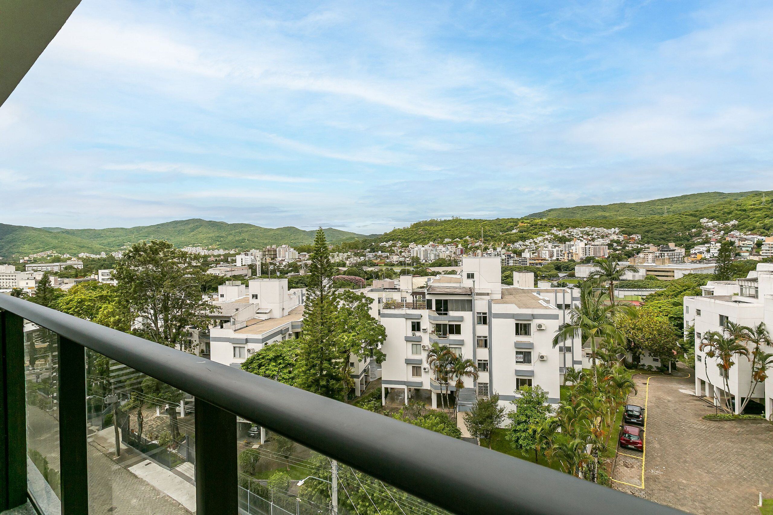 A residential area with modern buildings, a clear sky, and a hilly landscape in the background.