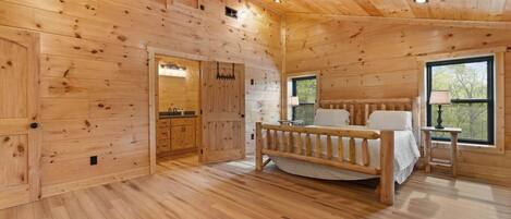 A wooden cabin interior with a bed, a ceiling fan, and a window.