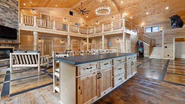 A spacious log cabin interior with a central island, multiple seating areas, and a fireplace. - Shawnee Creek Bourbon Trail Chalet (Mercer County)