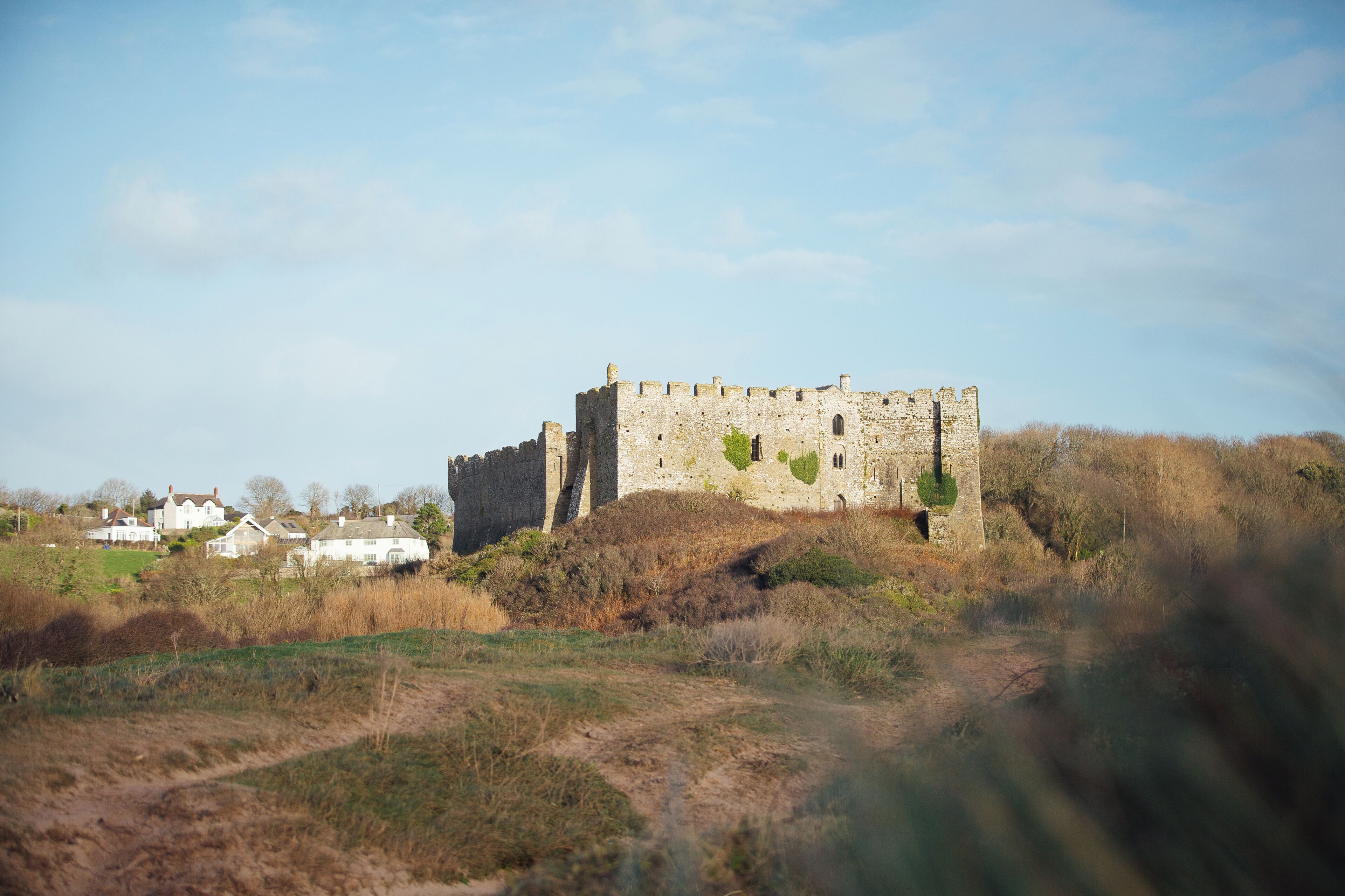 A historic stone castle on a hill with a clear sky.