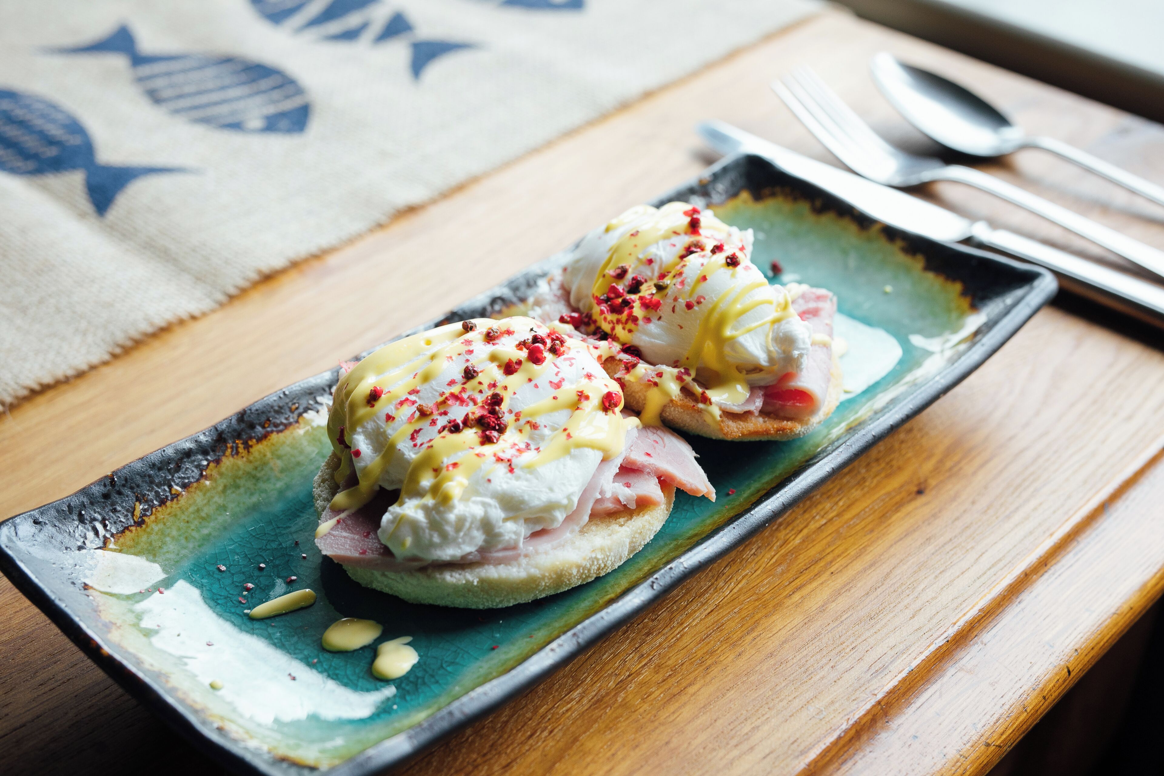 Ein Teller mit zwei Eggs Benedict Sandwiches auf einer Keramikteller.