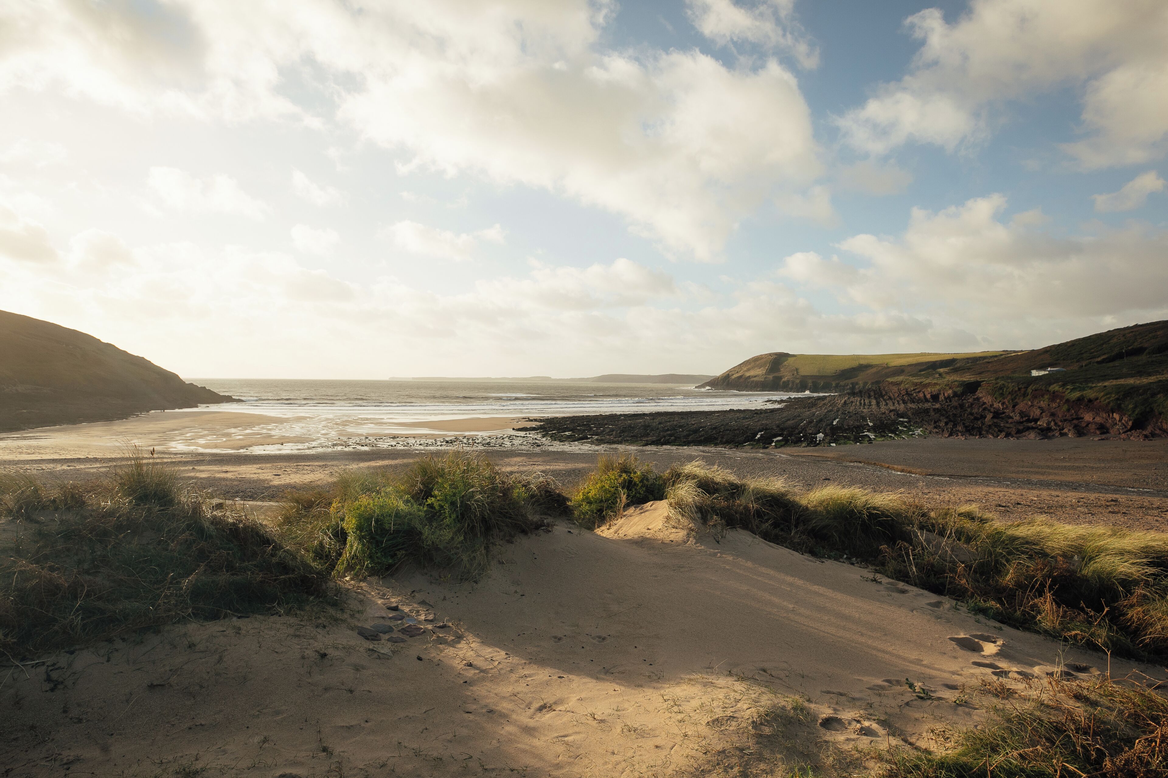 A coastal landscape with sandy terrain and grassy areas.