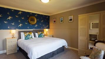 A bedroom with a bed, nightstands, a dresser, a chair, and a wall with a circular mirror.