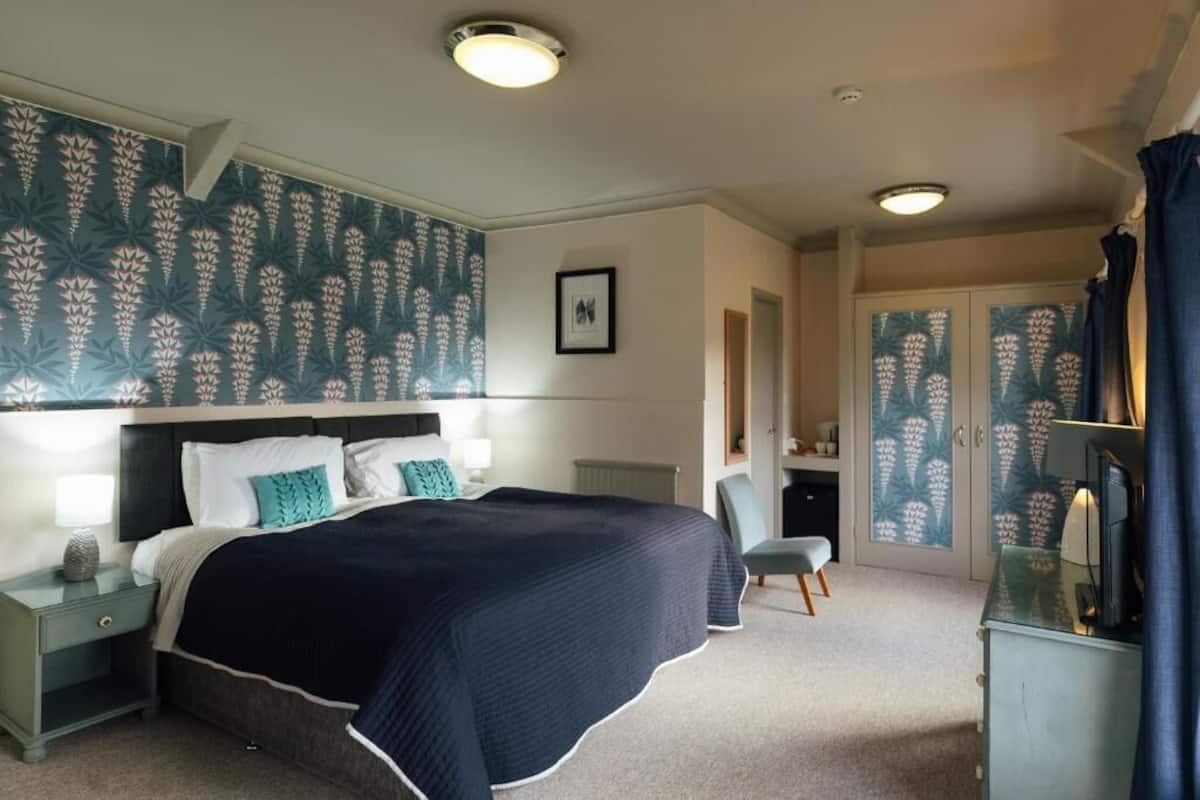 A bedroom with a bed, nightstands, a chair, a dresser, and a wardrobe with patterned doors.