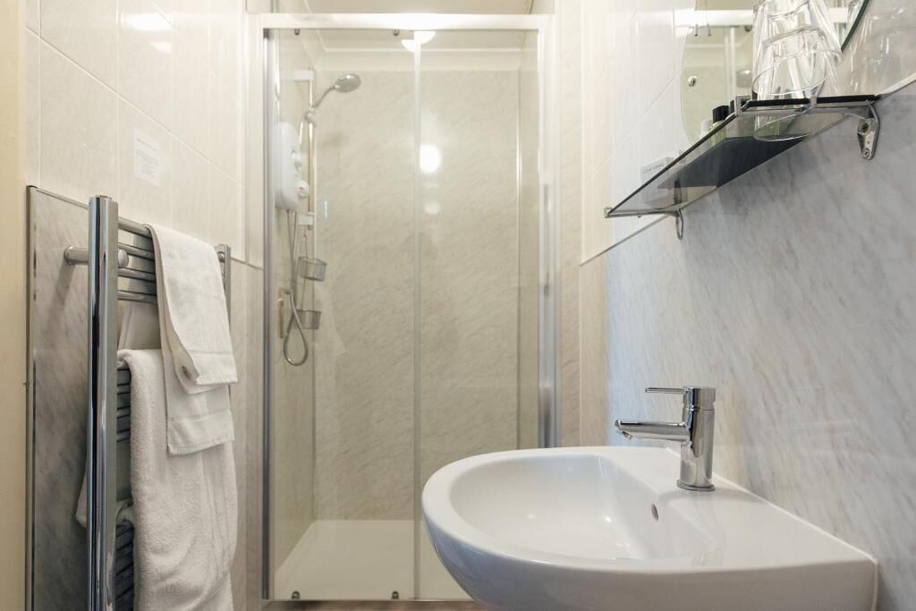 Uma casa de banho moderna com cabine de duche em vidro, uma sanita branca e um porta-toalhas.