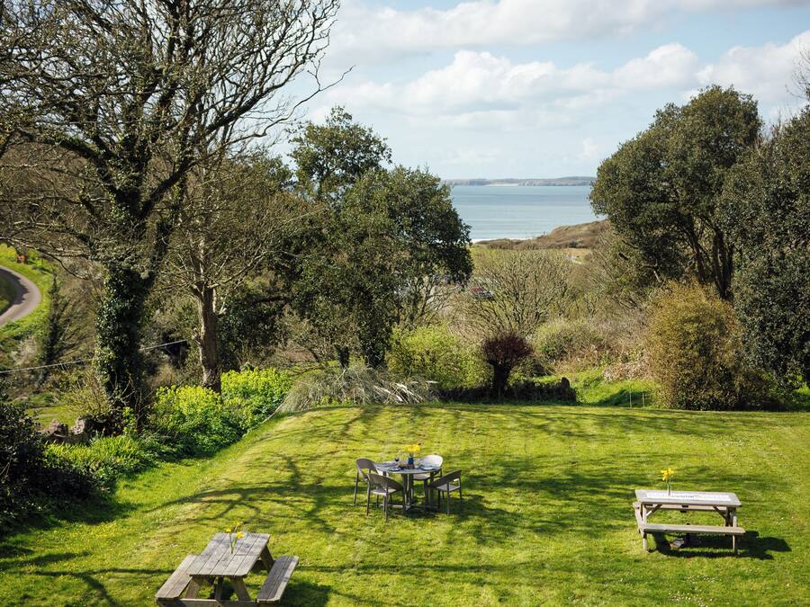 Zona verde con mesas de picnic y vista al mar.